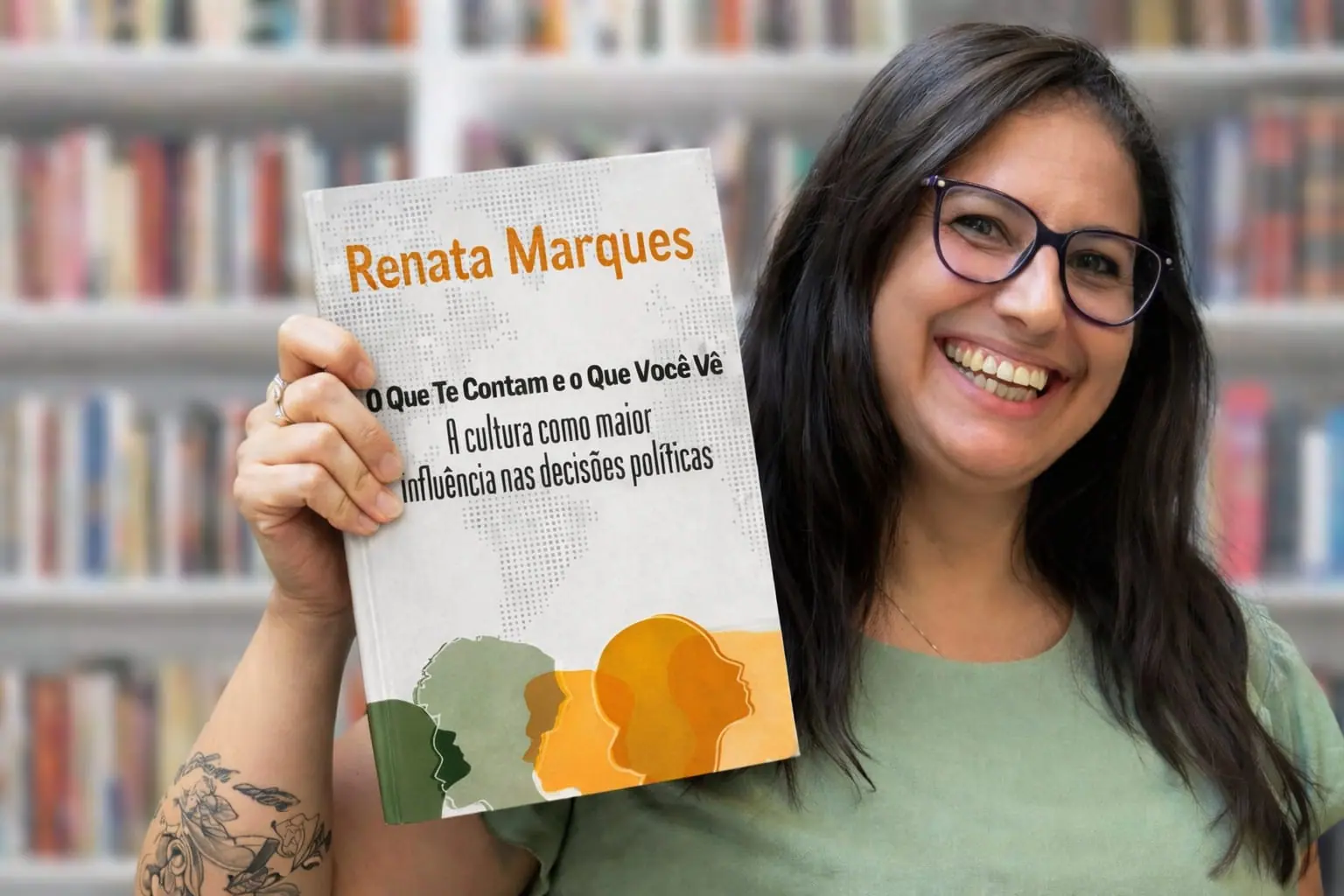 Renata Marques sorrindo, com o livro O Que Te Contam e o Que Você Vê na mão